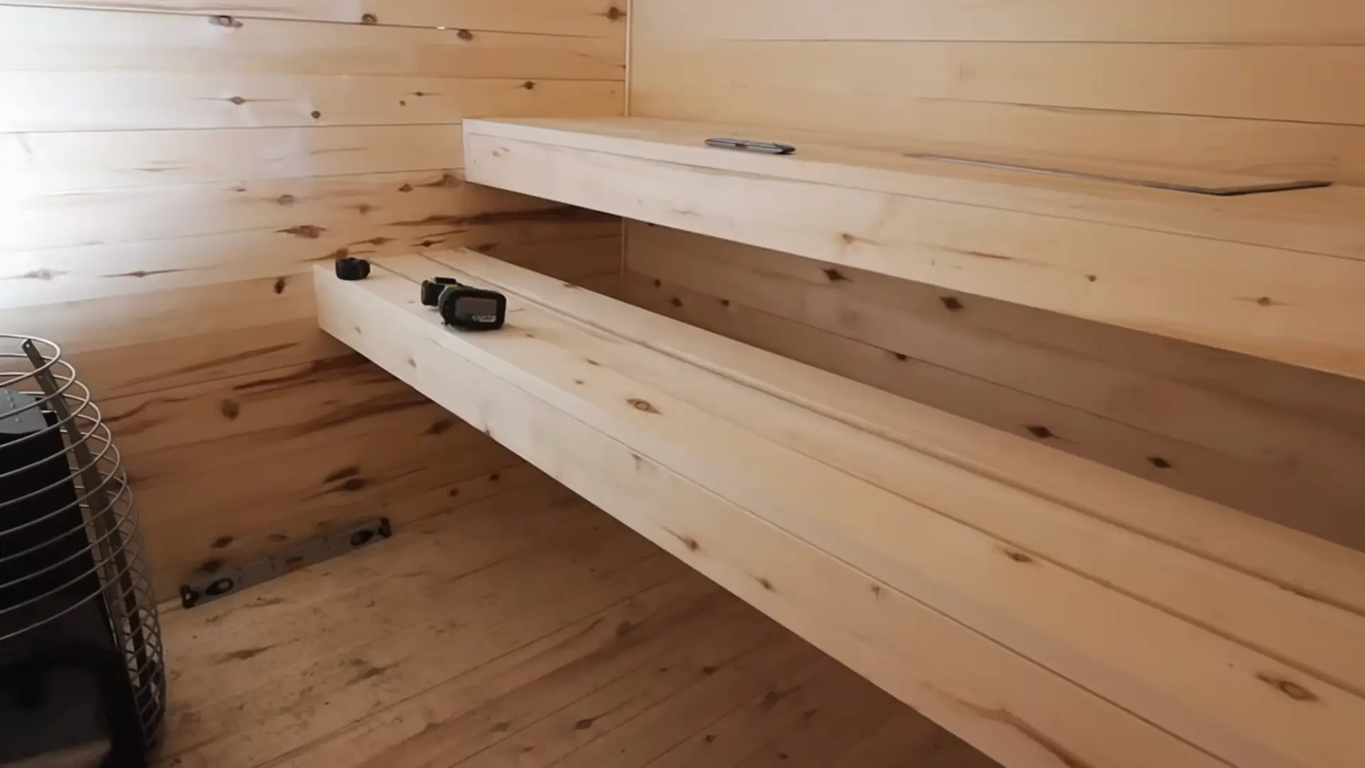 two-tier aspen wood sauna benches built from boards positioned at different heights next to a wood burning stove inside