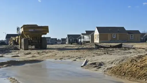 Construction site with unfinished houses and large dump truck under clear blue sky