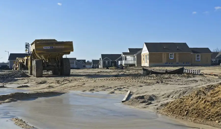 Construction site with unfinished houses and large dump truck under clear blue sky