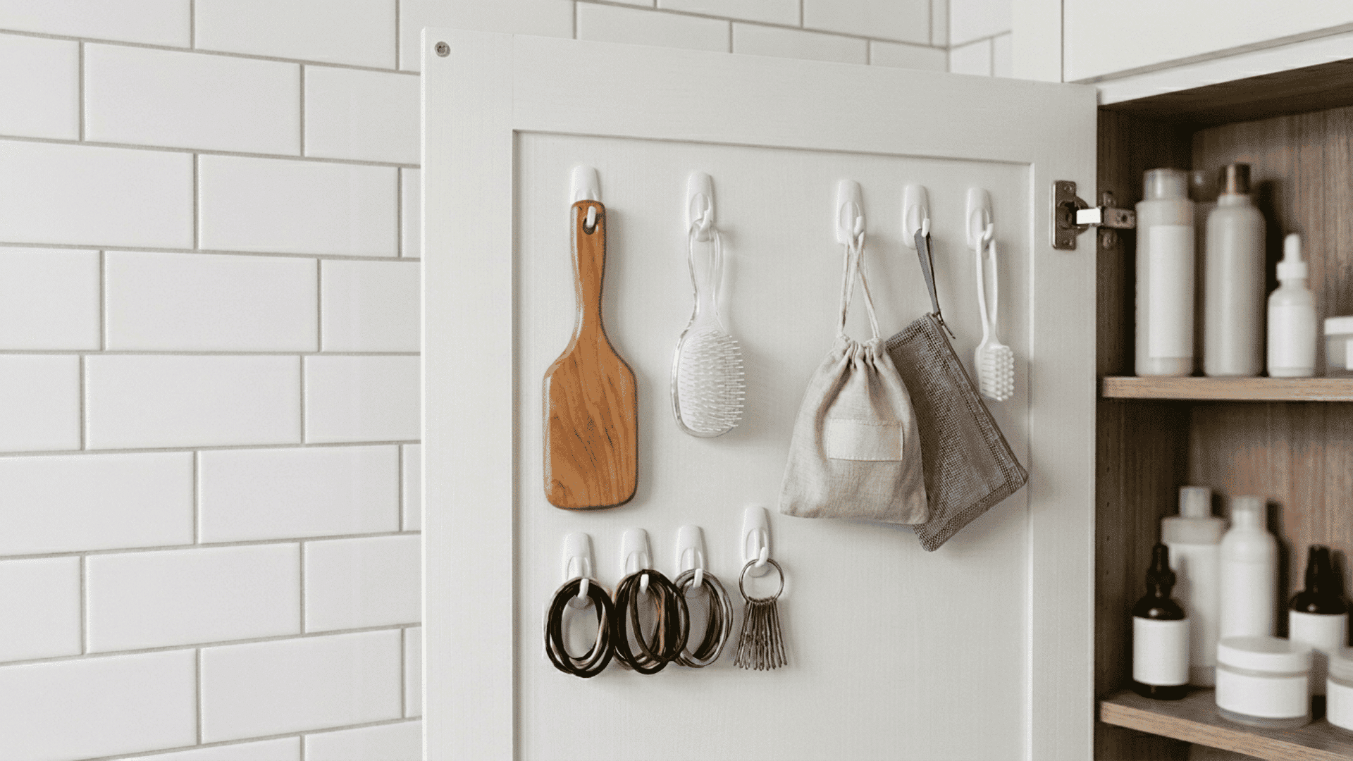 white metal over-the-door hooks hanging on a dark gray cabinet door holding a loofah and a towel.