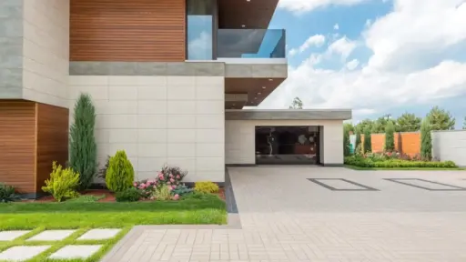 Modern house exterior with wooden accents, spacious driveway, and landscaped garden under a blue sky
