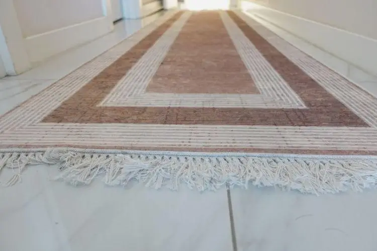 Geometric-patterned hallway runner rug with fringed edges on white tiled floor