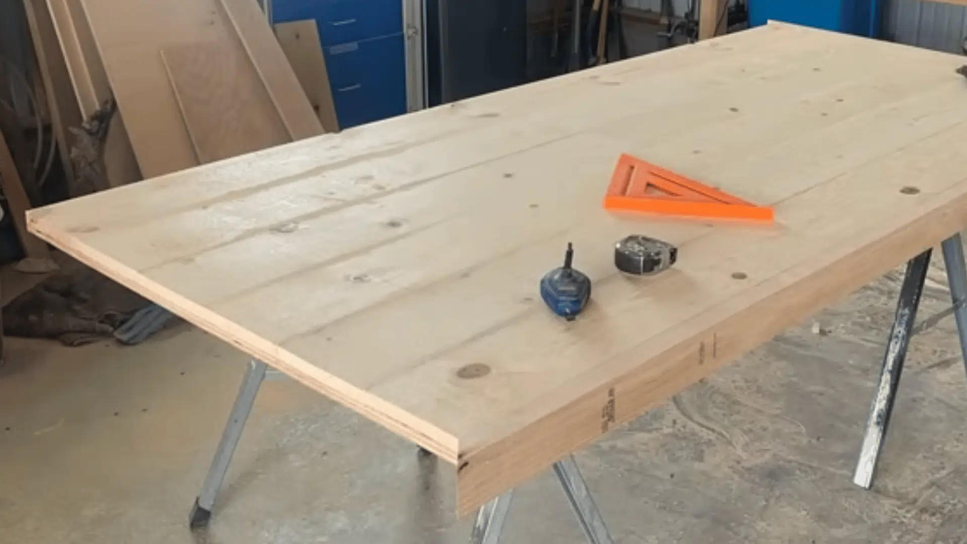 a completed wooden tabletop with measuring tools and a nail gun placed on its surface in a workshop