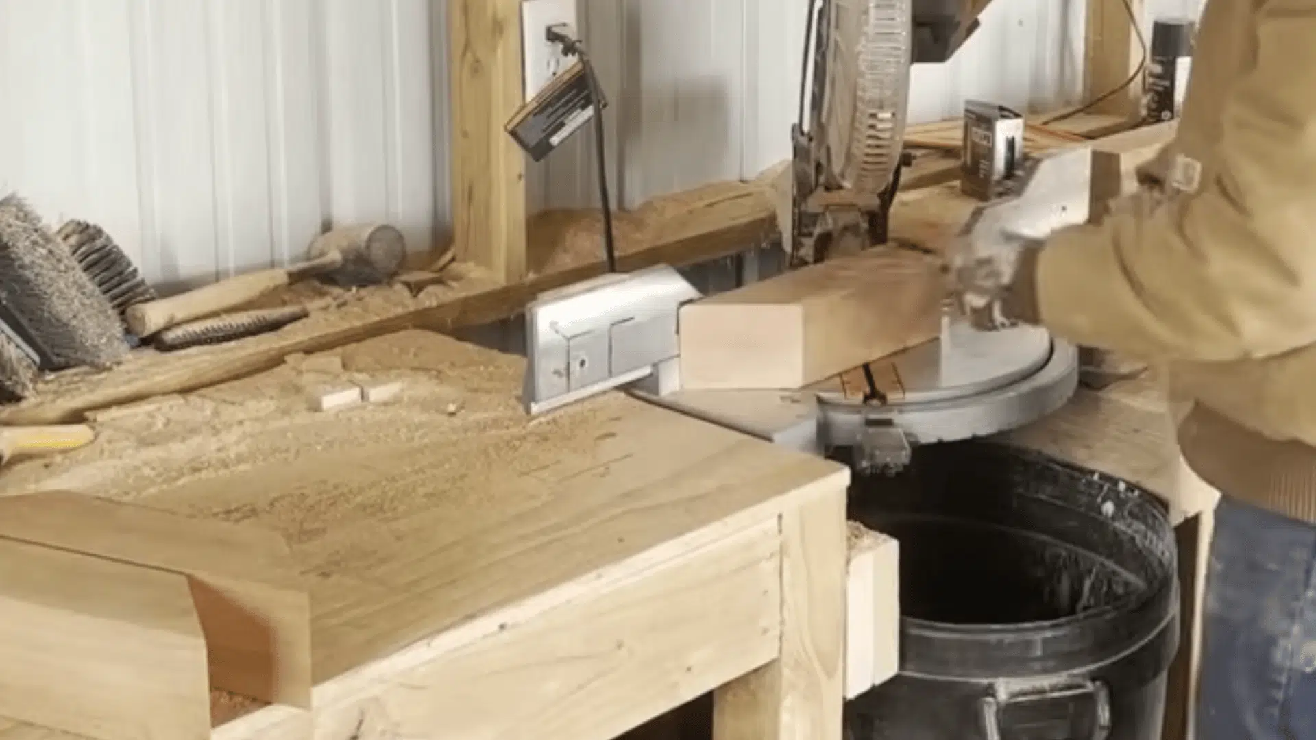 a woodworker cutting angled timber pieces with a miter saw on a sawdust covered workbench inside a workshop
