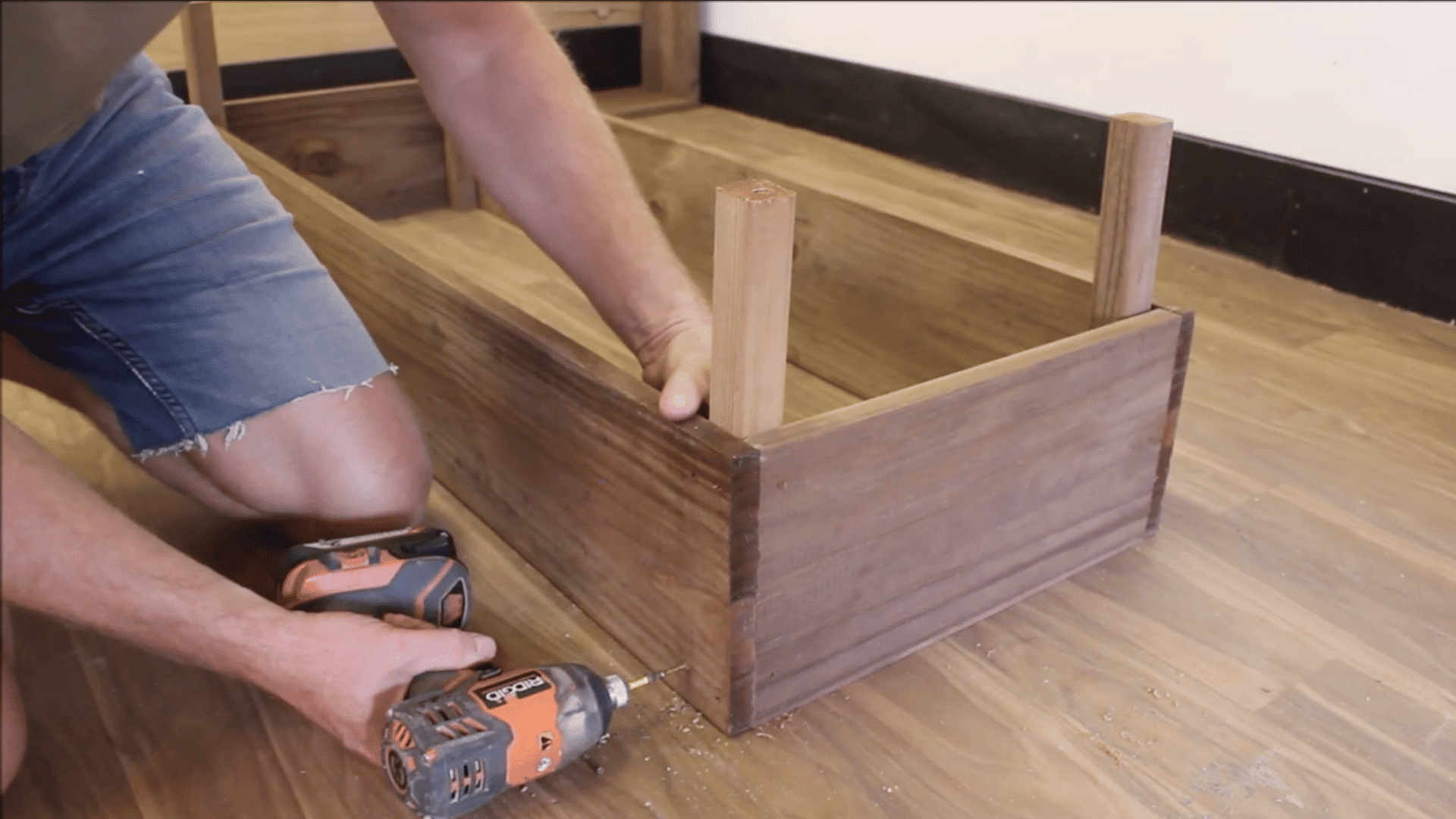 boards being affixed to wooden stabilizers to maintain the frame of the structure by man on wooden furnished floor