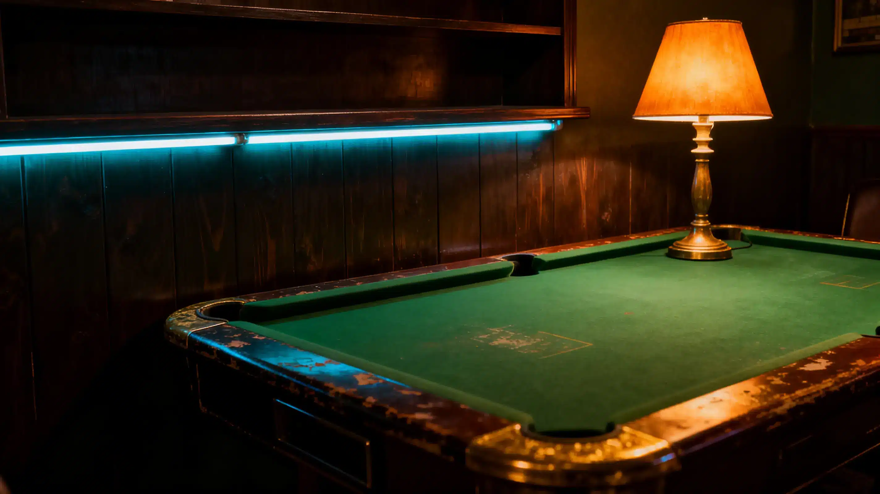 Dimly lit vintage billiard table with brass lamp in cozy wooden-paneled room