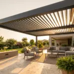 Modern outdoor patio with seating under a pergola, surrounded by lush greenery at sunset