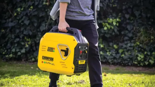 Person carrying yellow portable generator outdoors on grass with greenery background