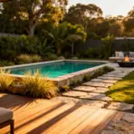 Poolside patio with outdoor seating and fire pit surrounded by lush greenery and sunset lighting