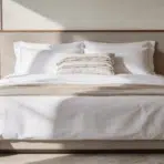 hotel inspired bed with crisp white bedding symmetrical pillows and layered textures in cozy modern bedroom