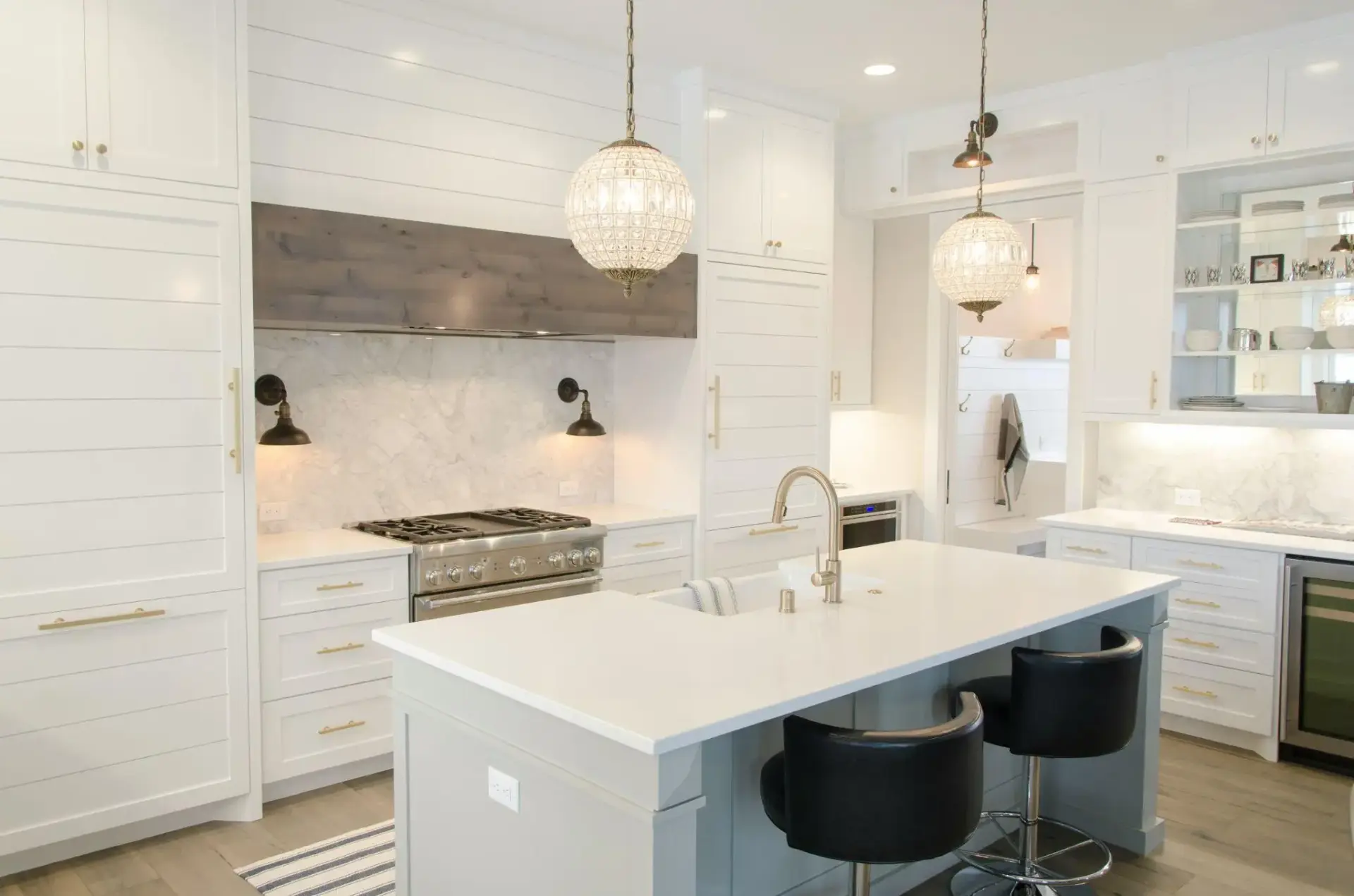 Modern white kitchen with marble backsplash, pendant lighting, and stainless steel appliances