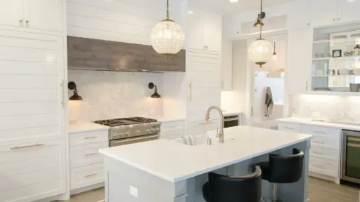 Modern white kitchen with marble backsplash, pendant lighting, and stainless steel appliances
