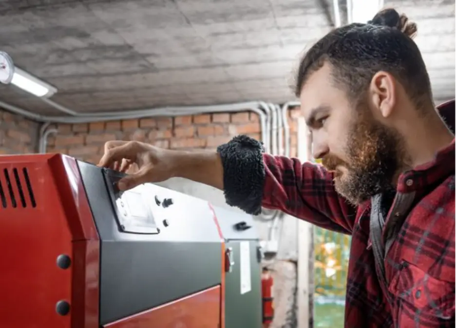 Man adjusting control panel on red industrial machine in brick-walled workshop