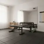 Home gym with dumbbells, bench, and exercise bands in minimalistic room with large mirror
