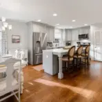 Spacious kitchen and dining area with hardwood floors and modern white cabinetry