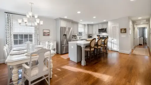 Spacious kitchen and dining area with hardwood floors and modern white cabinetry
