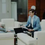 Three people in business attire having a discussion in a modern office lounge