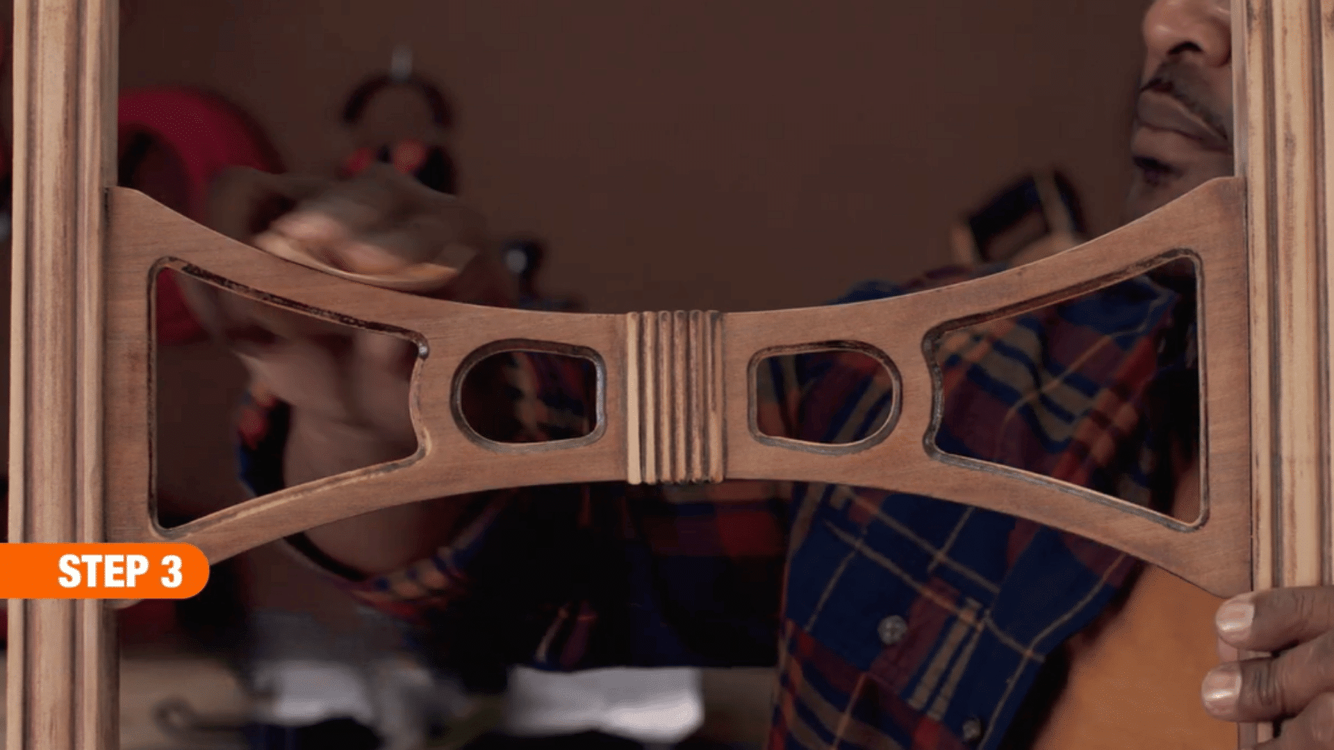 person hand sanding the decorative wooden backrest of a chair to create a smooth surface during furniture restoration