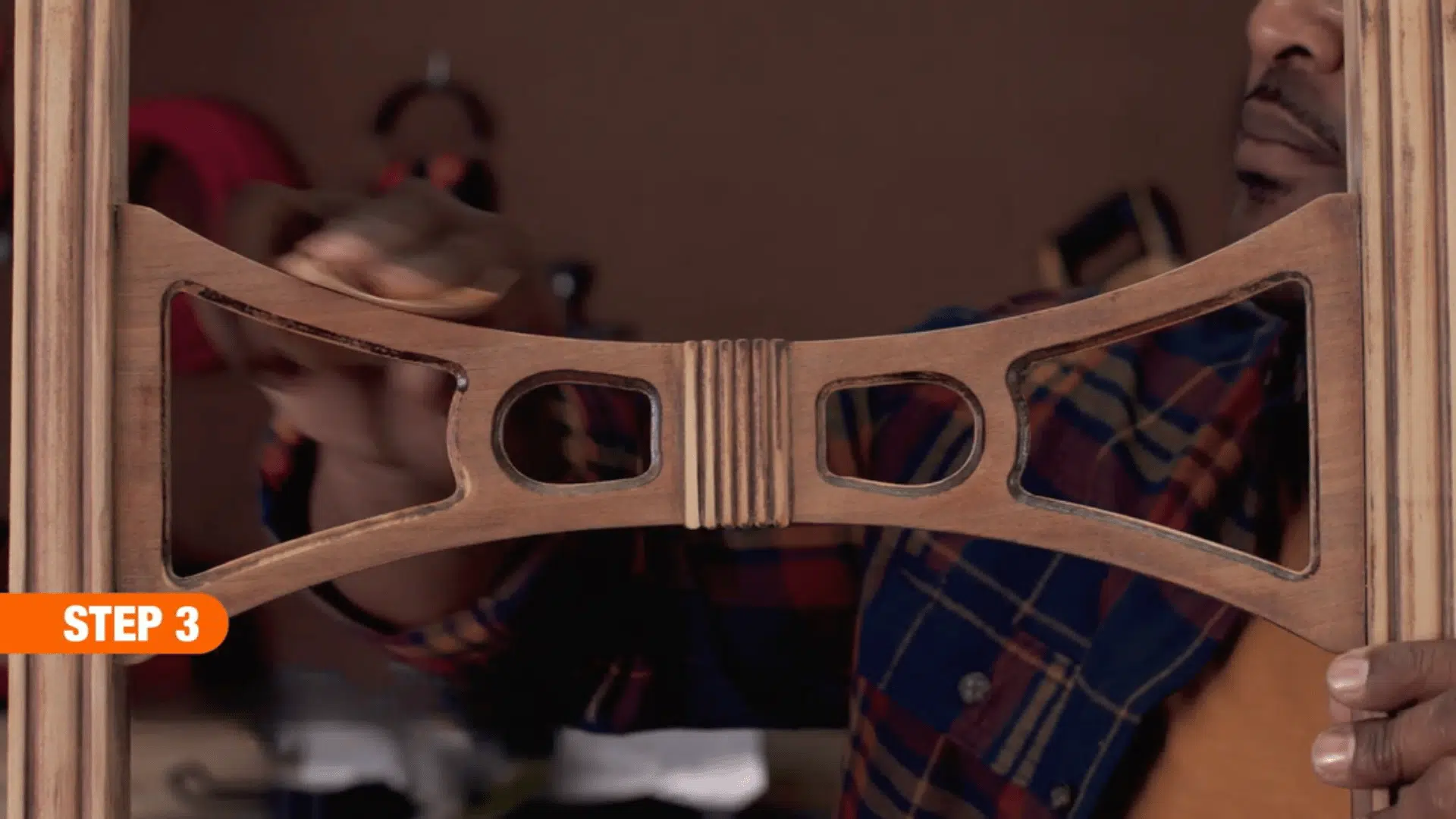 person hand sanding the decorative wooden backrest of a chair to create a smooth surface during furniture restoration