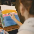 Artist painting colorful abstract scene on canvas in a cozy home studio
