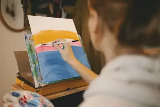Artist painting colorful abstract scene on canvas in a cozy home studio