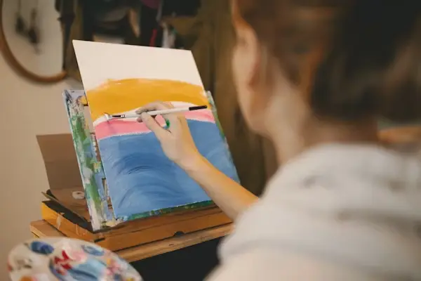 Artist painting colorful abstract scene on canvas in a cozy home studio