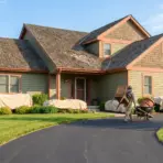 Man moving outdoor furniture with wheelbarrow in front of covered house patio