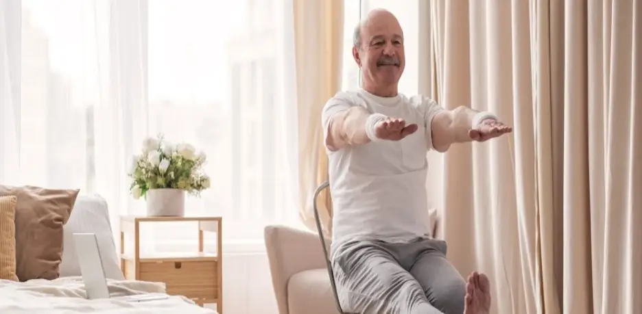 Elderly man doing seated exercises in bright, cozy bedroom with beige curtains