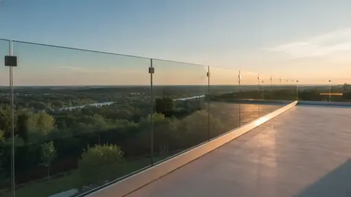 Glass terrace overlooking lush landscape at sunset with clear blue sky and distant horizon
