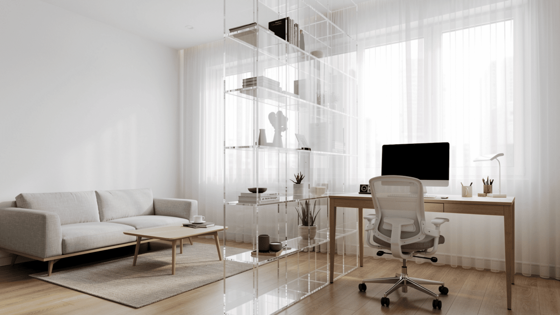 _a bright open plan apartment with a grey sofa and a transparent acrylic shelving unit dividing the living area from a home office with a computer desk