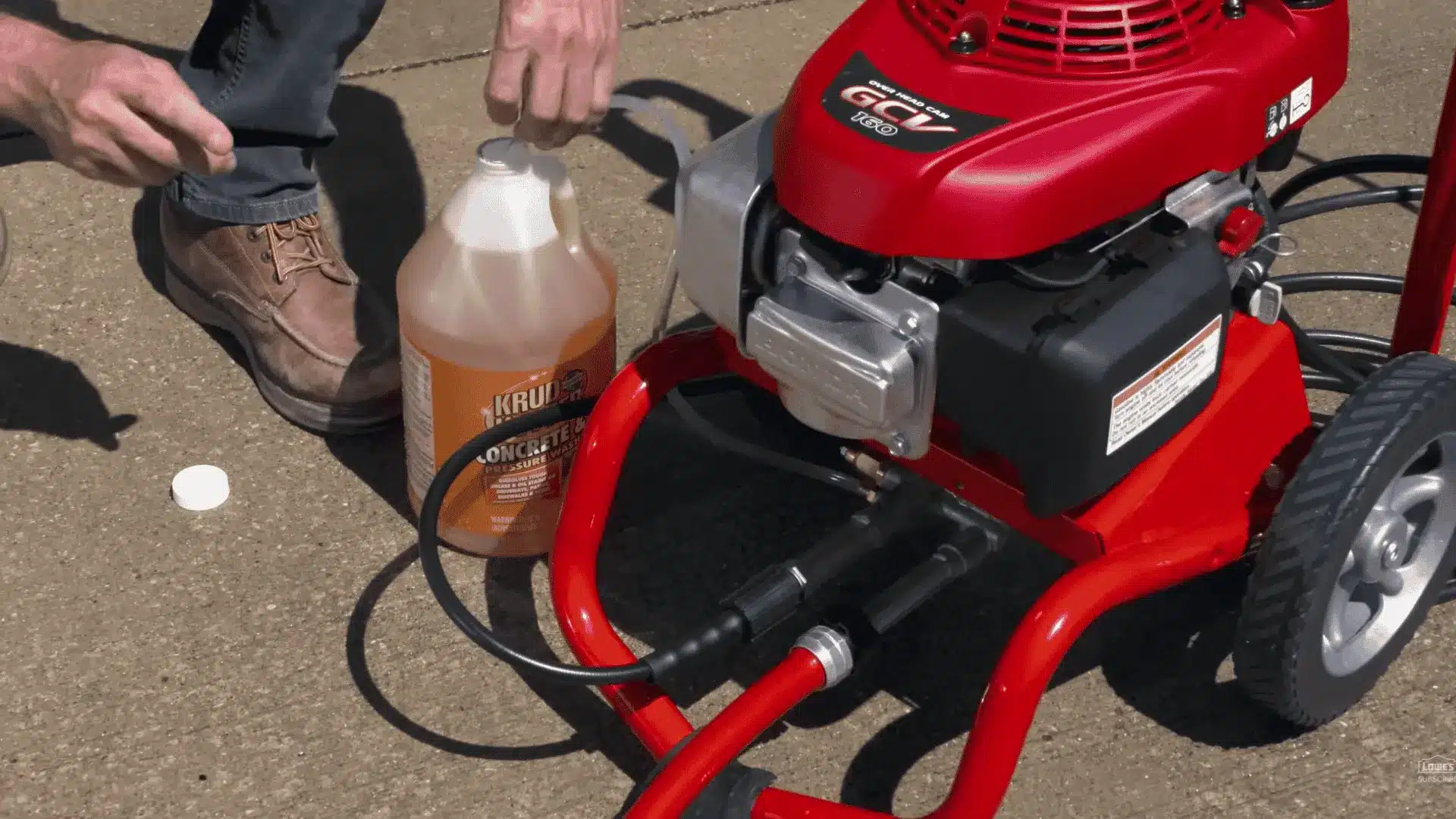 hands attaching a soap bottle of concrete cleaner and degreaser to a red pressure washer engine