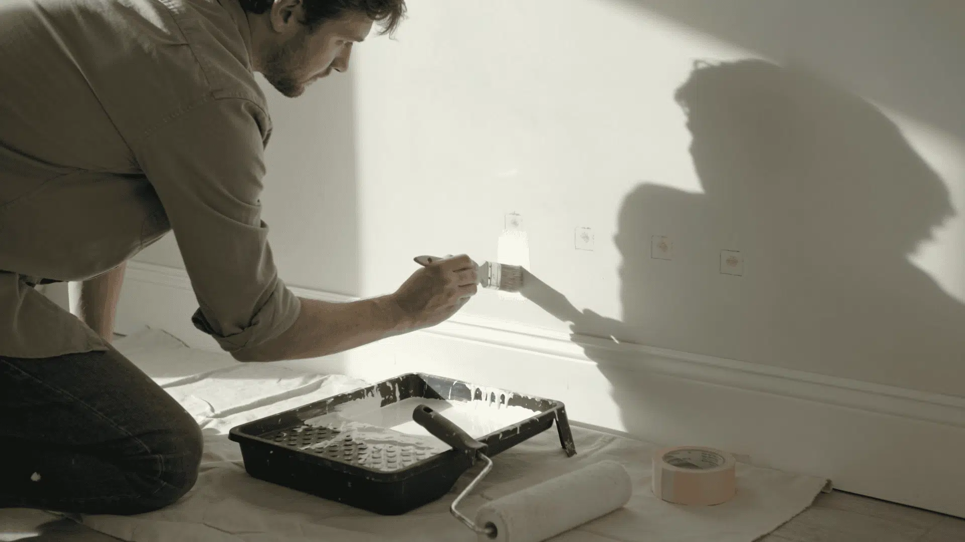 person touching up missed spots on a painted wall with a small brush