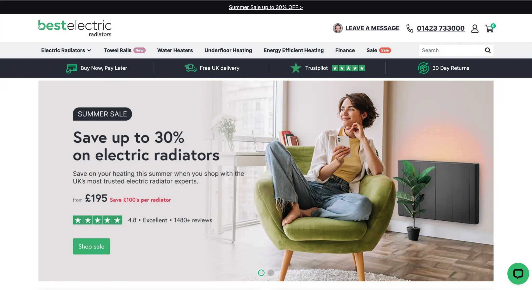 Woman sitting on green armchair using smartphone near electric radiator in modern room