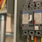 Industrial circuit breaker with visible wiring in a dimly lit electrical panel