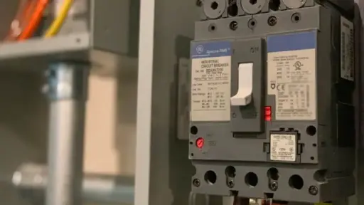 Industrial circuit breaker with visible wiring in a dimly lit electrical panel