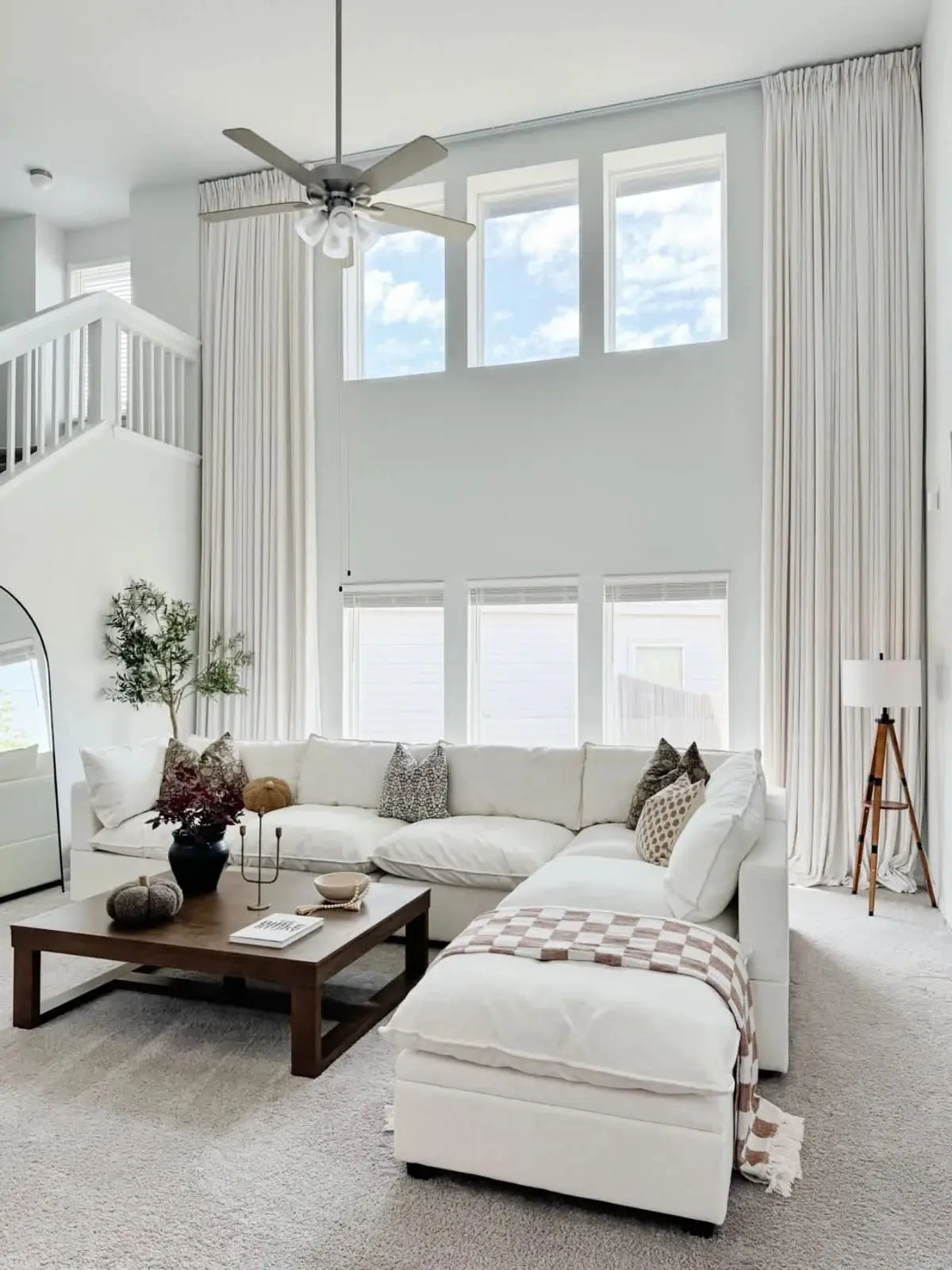 Spacious living room with white sectional sofa, wooden coffee table, and large windows with sheer curtains