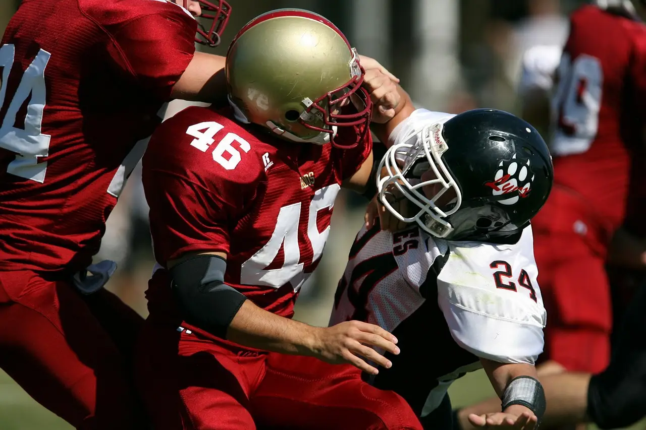 Football players in red and white uniforms tackling on the field during a game