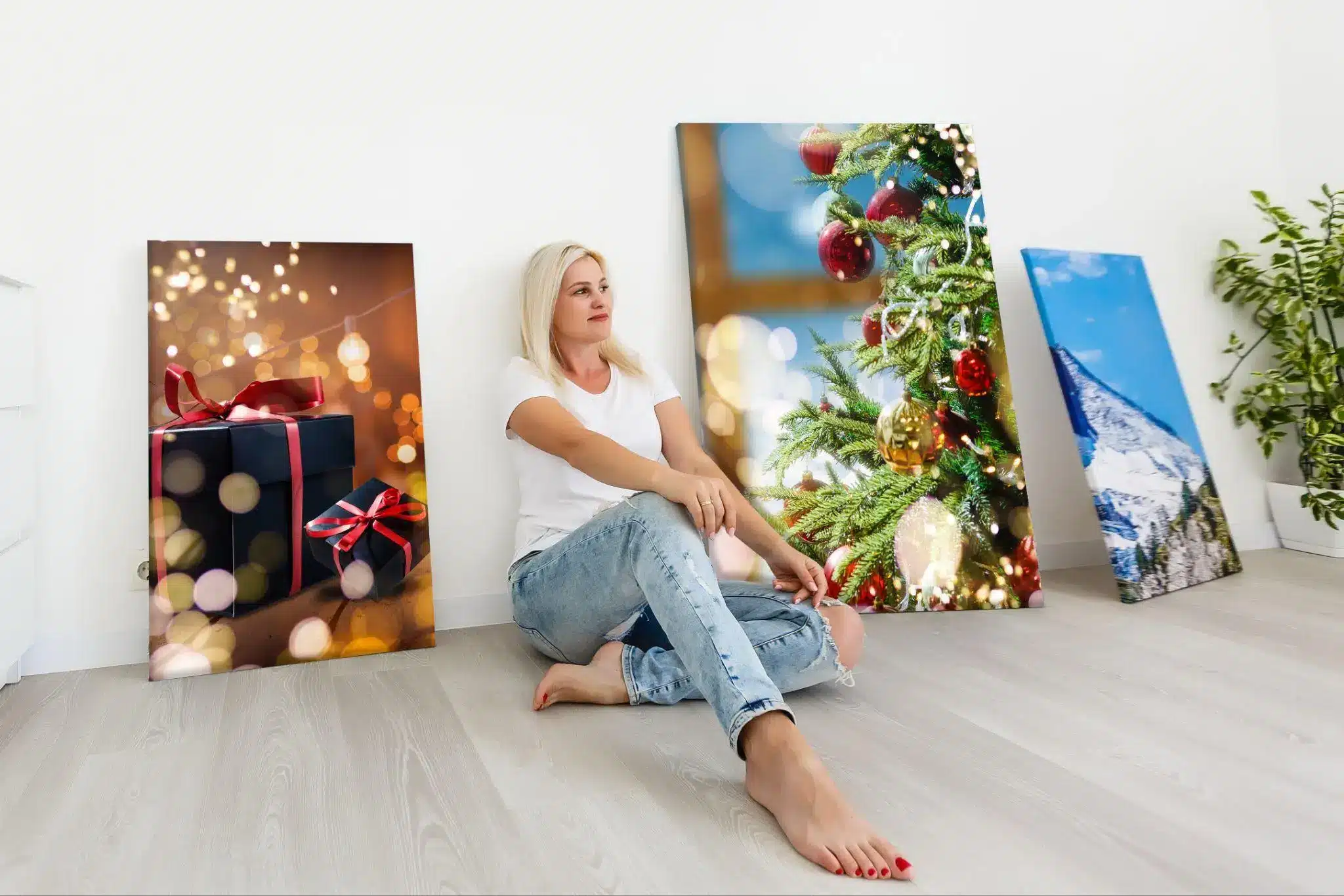 Woman sitting on floor surrounded by holiday-themed and nature paintings in a bright room