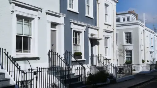 Row of pastel-colored terraced houses with wrought iron railings on a sunny street