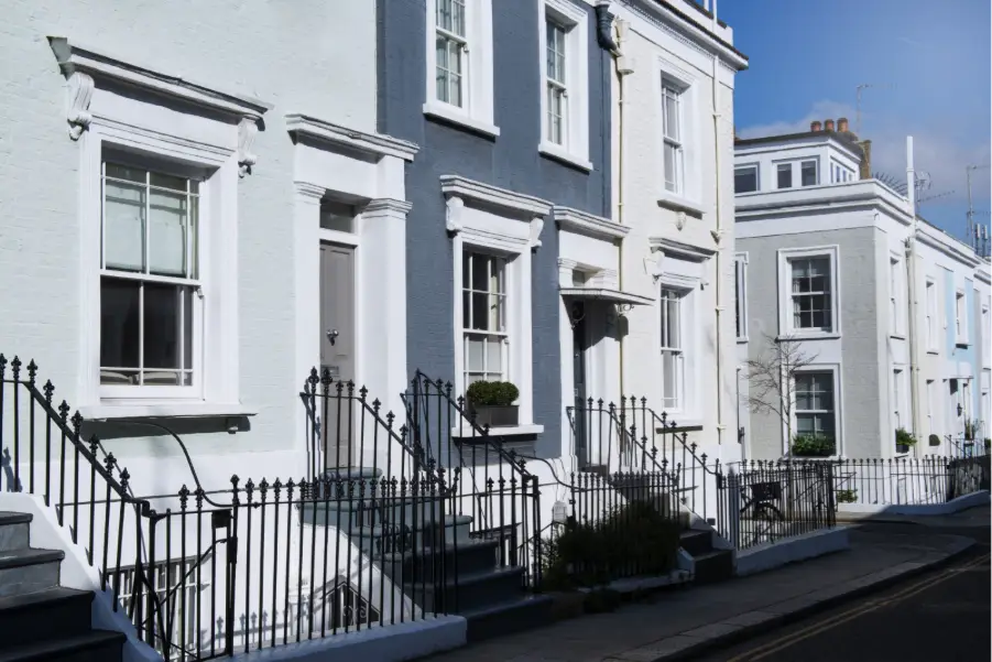 Row of pastel-colored terraced houses with wrought iron railings on a sunny street