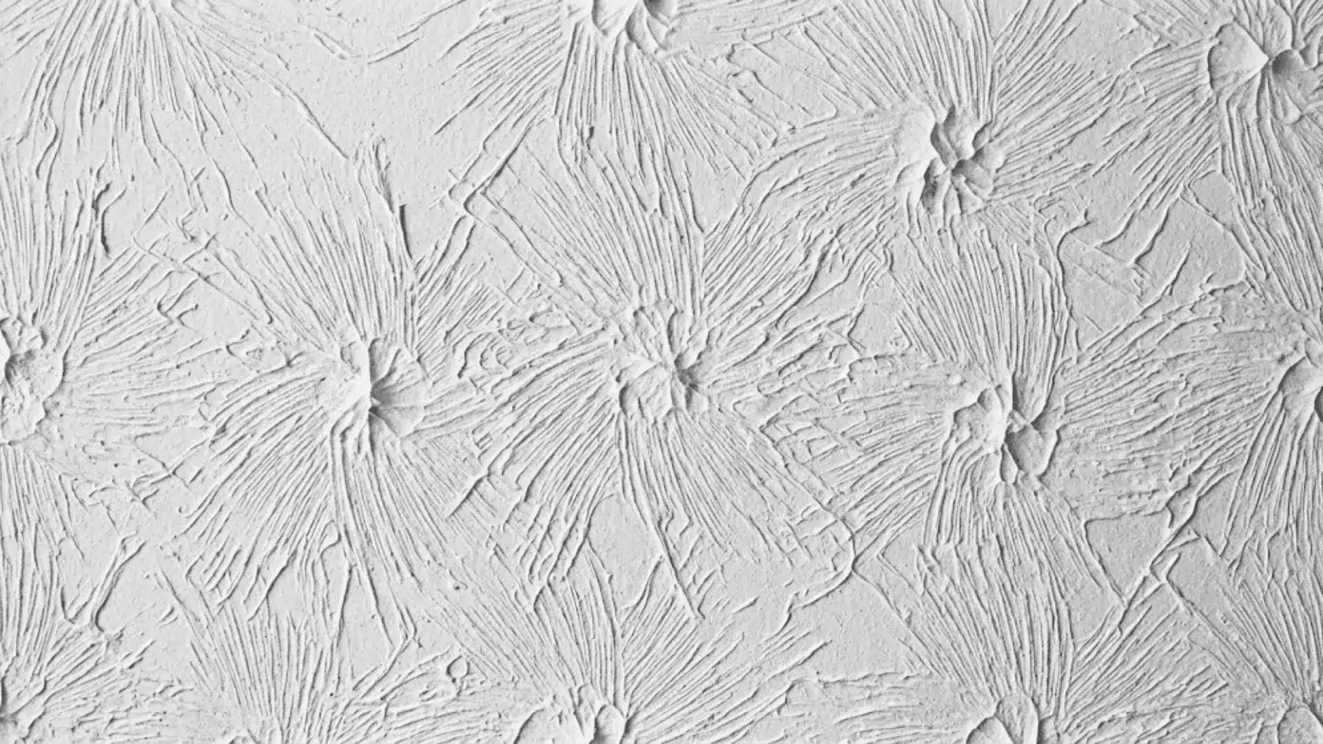extreme close-up of rosebud stomp ceiling texture showing dense radiating bristle impressions in white joint compound