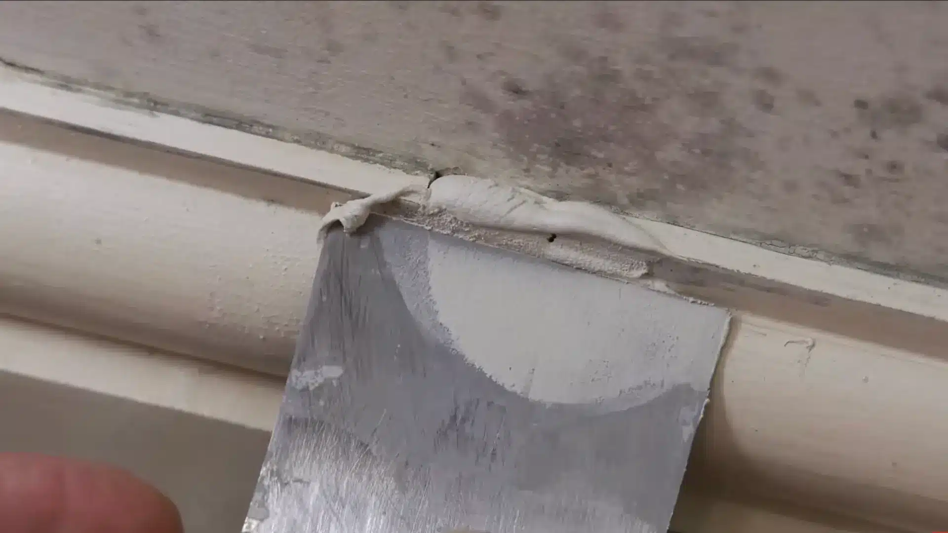 spatula applying pop or plaster over an edged breakage near the floor on the wall for deeper clean and repair
