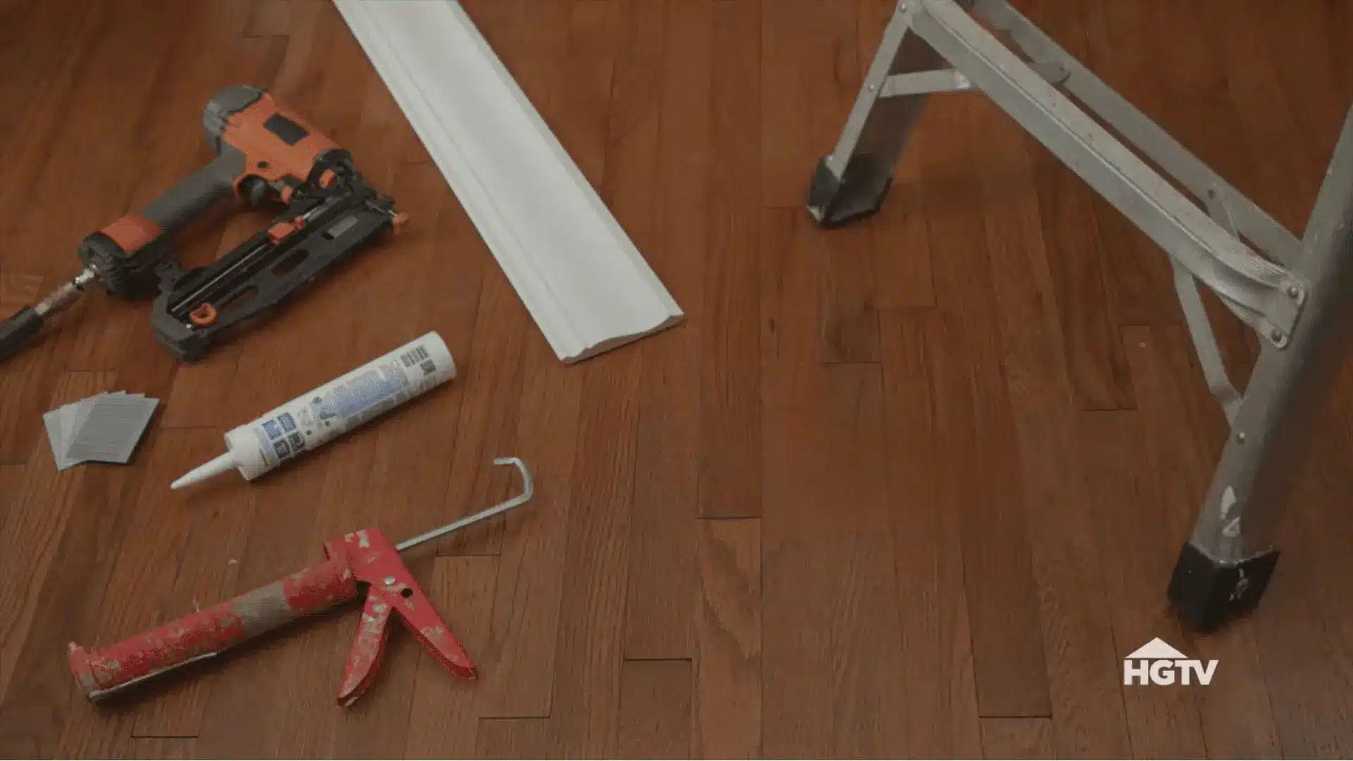 miter saw nail gun tape measure caulk and crown molding arranged neatly on a workbench before installation