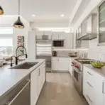 Modern kitchen with stainless steel appliances, white cabinets, and pendant lighting over island countertop