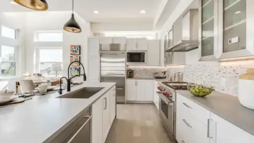 Modern kitchen with stainless steel appliances, white cabinets, and pendant lighting over island countertop