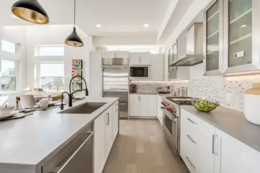 Modern kitchen with stainless steel appliances, white cabinets, and pendant lighting over island countertop