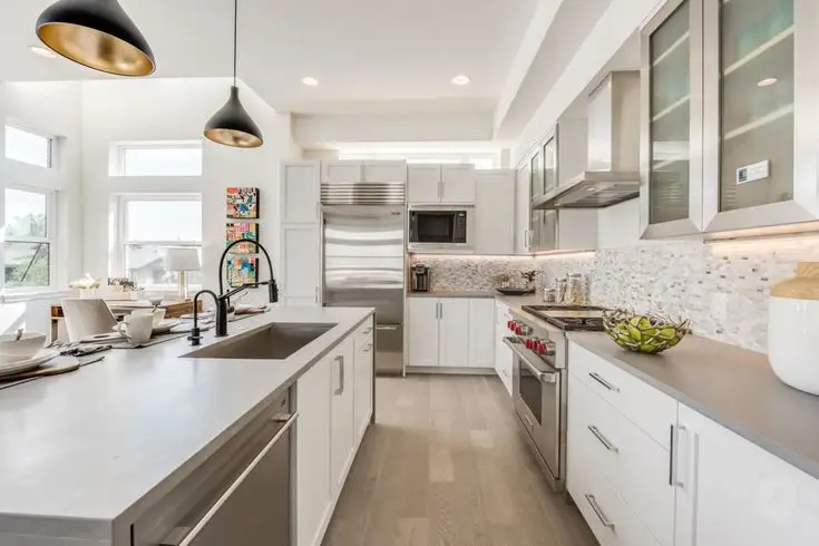 Modern kitchen with stainless steel appliances, white cabinets, and pendant lighting over island countertop