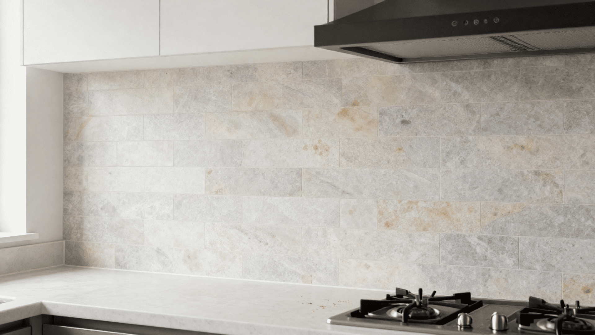 kitchen with tumbled limestone backsplash extending from countertop to ceiling beside a matte black range hood