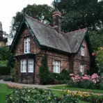 Charming brick cottage surrounded by lush garden and colorful flowers in a serene outdoor setting