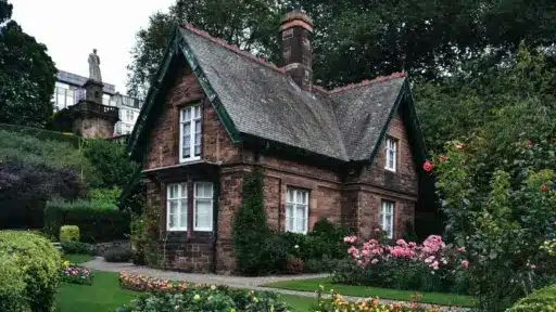 Charming brick cottage surrounded by lush garden and colorful flowers in a serene outdoor setting